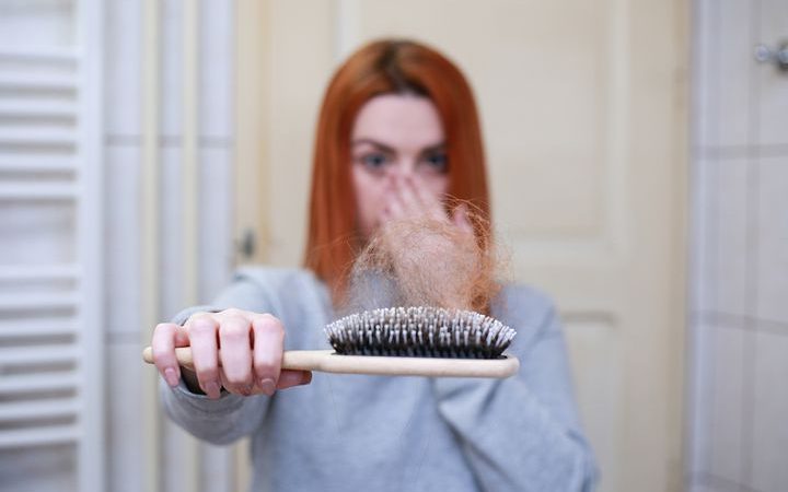 Woman suffering from hair loss showing a comb full of hair