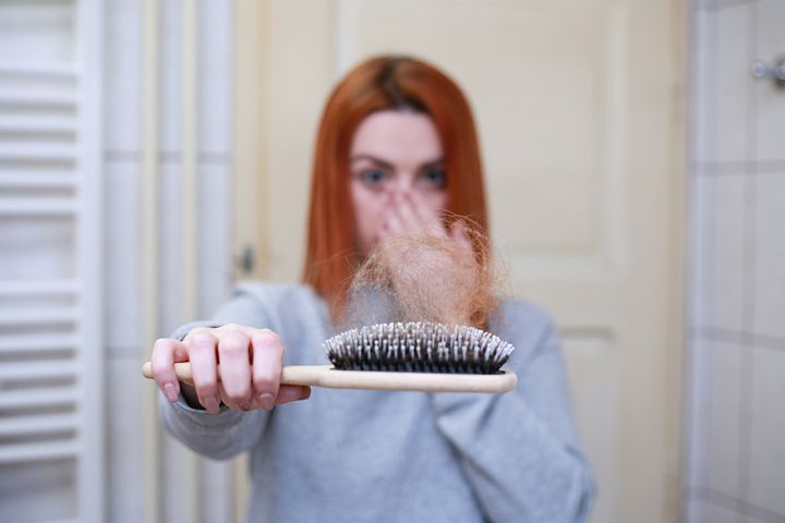 Woman suffering from hair loss showing a comb full of hair