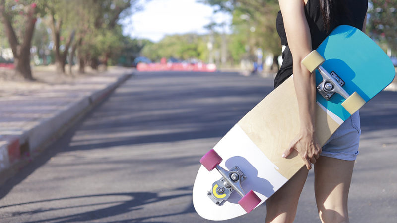 Woman holds a skateboard bought in an Australian skateboard shop