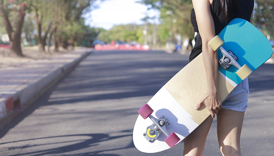 Woman holds a skateboard bought in an Australian skateboard shop